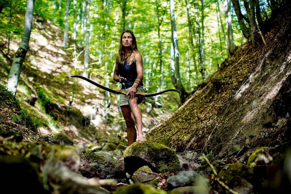 Miriam Lancewood équipée de son arc est en quête d'une proie dans la forêt