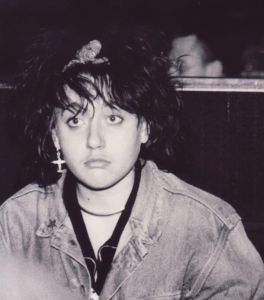 Portrait en noir et blanc de la jeune punk Virginie Despentes assise sur une banquette. 